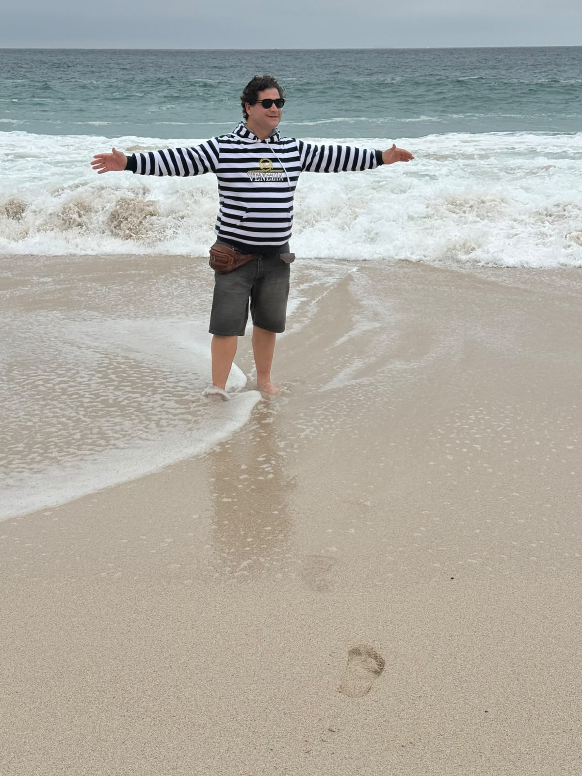 Nicco de braços abertos na praia, durante o trecho que fez a pé entre Cape Point e o Cabo da Boa Esperança